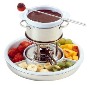 Réchaud com fondue de chocolate e frutas em volta.